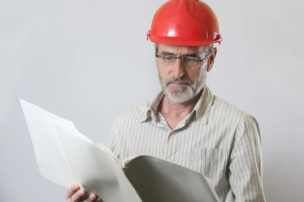 Potret seorang insinyur dengan helm dan kertas proyek — Stok Foto