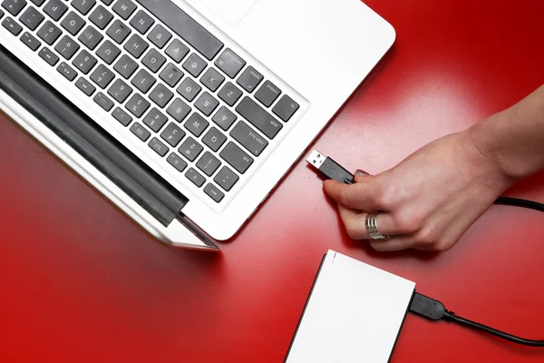 Bovenaanzicht van vrouwelijke hand externe harde schijf aansluiten op laptop — Stockfoto