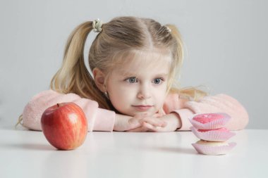 Tatlı Küçük Kız, Donut ve Elma Sağlıklı Atıştırmalık ve Çocukluk Konsepti arasında seçim yapıyor.