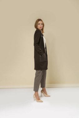 Sıradan giyinen kadın manken - Pamuk beyaz gömlek, Pamuk ve Deri Olmayan Cardigan, Yama Pockets ve Çıplak Yüksek Topuklu Sigara Kahverengi desenli Pantolon. Stüdyo çekimi.