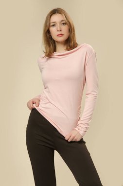 Yumuşak pamuklu, pembe uzun kollu gömlek giyen kadın model. Stüdyo çekimi.