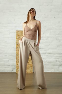 Minimalist Lüks Moda Kadını, bej gömlekli ve geniş bacaklı pantolon giyiyor.
