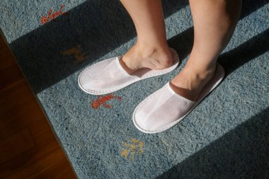 Beyaz otel terlikleri giyen kadın ayakları, yukarıdan manzara