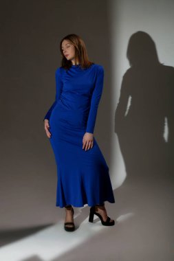 Kraliyet mavi tişörtü ve zarif etek koleksiyonu giyen bir kadın model.