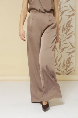 Geniş ipek bej pantolon giyen kadın model. Klasik ve zamansız basit moda. Stüdyo çekimi.