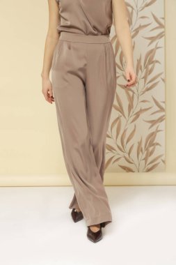 Geniş ipek bej pantolon giyen kadın model. Klasik ve zamansız basit moda. Stüdyo çekimi.