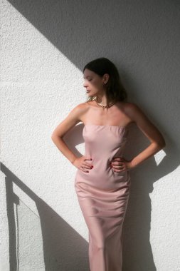 Yazın soluk pembe saten askısız gelinlik giyen kadın manken. Zarif straplez kolsuz maksimum elbiseli kadın..
