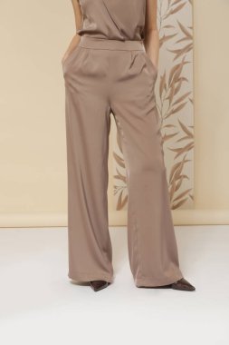 Geniş ipek bej pantolon giyen kadın model. Klasik ve zamansız basit moda. Stüdyo çekimi.