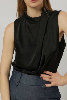 Uzun kollu beyaz ipek bluz giyen, kıvrık boyunlu ve yüksek bel pantolon giyen kadın model.