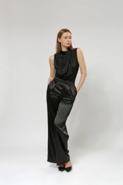 Siyah bluz giyen kadın model ve geniş saten siyah pantolon. Klasik ve zamansız basit moda. Stüdyo çekimi.