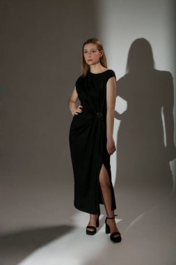 Sofistike ve zarif minimalist moda koleksiyonu için önü güzelce örtülmüş siyah Maxi elbise giyen kadın model portresi.