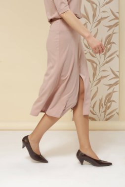 Tek renkli pembe elbise giyen bir kadın manken. Klasik kısa kollu bluz ve Midi eteği. Moda stüdyosu çekimi.