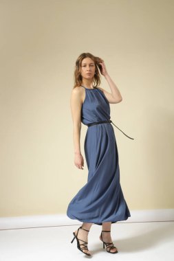 Mavi Maxi Camisole elbisesi giymiş genç bir kadının stüdyo fotoğraflarının serisi. Gündelik ve şık yaz kıyafetleri, bahar-yaz moda trendi.