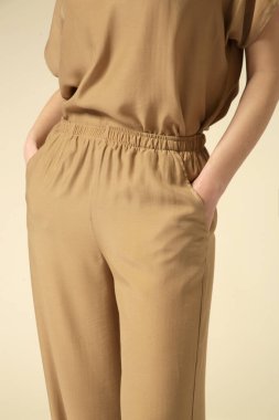 Tek renkli altın bej elbise giyen bir kadın model. Klasik ve zamansız basit bluz ve geniş bacak pantolonu. Moda stüdyosu çekimi.