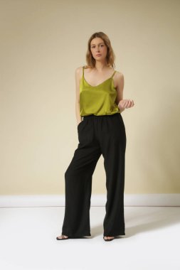 Stüdyo fotoğrafları. İpek elbiseli genç kadın manken, yeşil gecelik bluz ve siyah geniş paça pantolon.