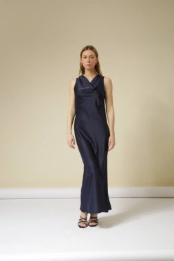 Stüdyo fotoğraflarında koyu mavi ipek elbise giyen kadın modeller var. Zarif asgari moda.