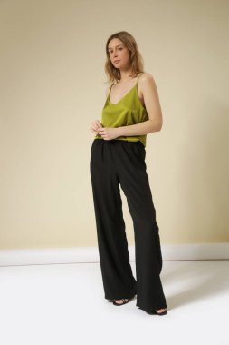 Stüdyo fotoğrafları. İpek elbiseli genç kadın manken, yeşil gecelik bluz ve siyah geniş paça pantolon.