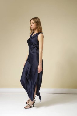 Stüdyo fotoğraflarında koyu mavi ipek elbise giyen kadın modeller var. Zarif asgari moda.