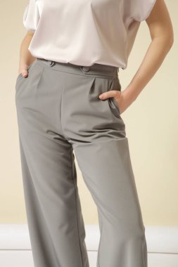 Açık gri, akıllı, rahat, özel dikim, yüksek paçalı pantolon giyen bir kadın model. Stüdyo çekimi.