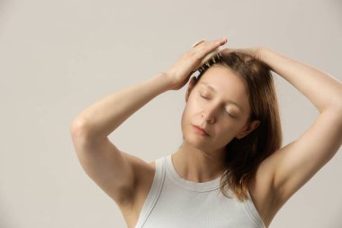 Kafa masajı yapan bir kız kafa masajı yapıyor, saç büyümesini teşvik ediyor, mikro dolaşımı sağlıyor, doğal yağları kafa derisine daha eşit dağıtmaya yardımcı oluyor.