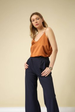 Lacivert çizgili beyaz çizgili, kahverengi Cami bluzlu, yüksek katlı bir pantolon giyen kadın model. Stüdyo çekimi.