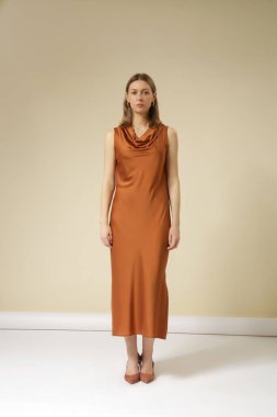 Stüdyo fotoğraflarında altın rengi kahverengi ipek elbise giyen kadın modeller. Zarif asgari moda.
