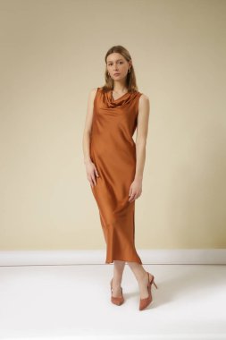 Stüdyo fotoğraflarında altın rengi kahverengi ipek elbise giyen kadın modeller. Zarif asgari moda.