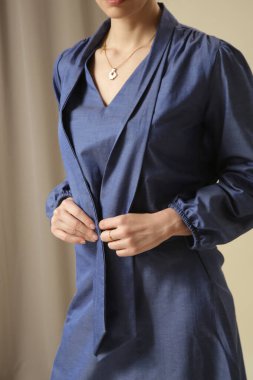 Tek renkli kot pantolon giyen kadın bir manken. Midi etek ve papyon yaka bluz. Moda stüdyosu çekimi.