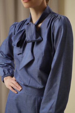 Tek renkli kot pantolon giyen kadın bir manken. Midi etek ve papyon yaka bluz. Moda stüdyosu çekimi.