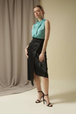 Siyah ipek etek ve nane rengi papyon yaka bluz giyen bir kadın model. Moda stüdyosu çekimi.