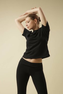 Temel siyah pamuklu tişörtlü ve dörtte üçlük kesilmiş taytlı bir kadın model..
