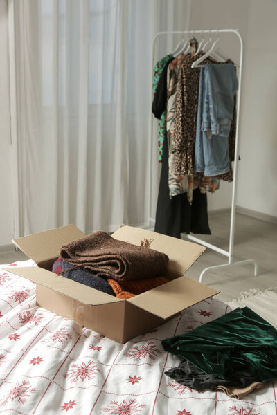 Spring Cleaning Organization, Decluttering, Moving and Donation Concept  Woman Sorting and Packing Clothes into Cardboard Box at Home