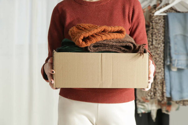 Spring Cleaning Organization, Decluttering, Moving and Donation Concept  Woman Sorting and Packing Clothes into Cardboard Box at Home