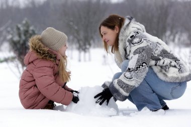 Anne ve Kızı Karlı Kış manzarasında birlikte vakit geçiriyorlar.
