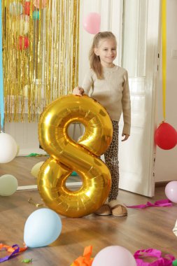 Doğum günü partisinden sonraki sekiz numaralı balonun yanında fotoğraf çeken mutlu küçük kız doğum günü kutlaması konsepti