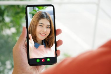 Video konferansı, mutlu bir kızın cep telefonuyla görüntülü konuşması, Asyalı bir kadının akıllı telefondan görüntülü konuşması, ailesiyle selamlaşması, arkadaşı, internet telekomünikasyon, sosyal mesafeli konuşma... 