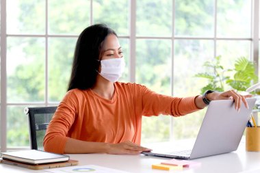 Coronavirus, koruyucu maske takan Asyalı kadın, Koronavirüs yüzünden karantinada olan Asyalı kız dizüstü bilgisayar kullanırken koruyucu maske takıyor.