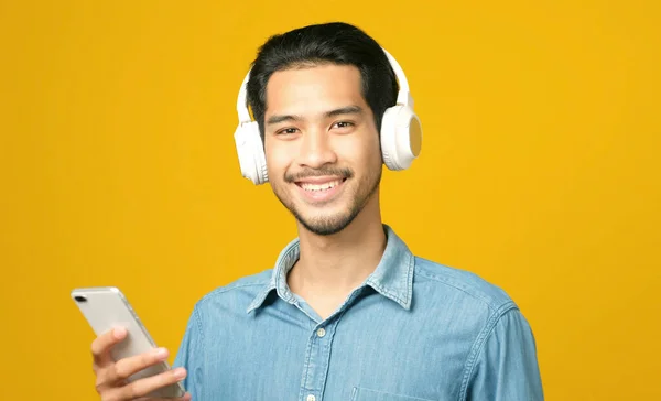 Uomo Asiatico Con Cuffie Possesso Telefono Cellulare Guardando Fotocamera Sorridendo — Foto Stock