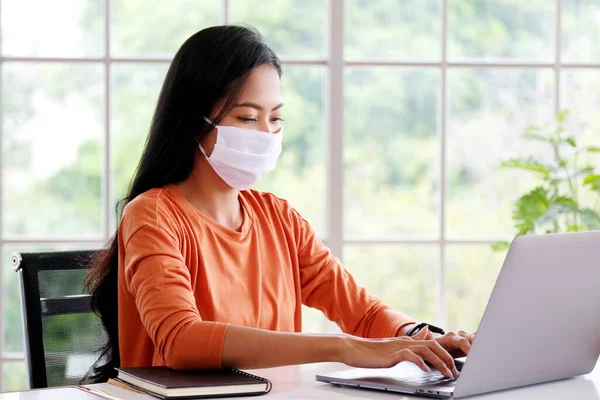 Coronavirus, koruyucu maske takan Asyalı kadın, Koronavirüs yüzünden karantinada olan Asyalı kız, dizüstü bilgisayar kullanırken koruyucu maske takıyor.