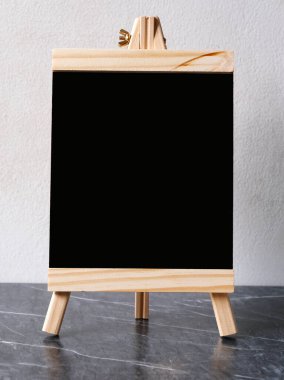 Boş siyah tahta menü tahtası, yazı tahtası, fotokopi alanı, şablon, kafeterya için karatahta, restoran menüsü işareti arka planı olan beyaz beton duvarın üzerinde duruyor.