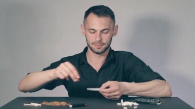 El yapımı sigarayı yuvarlayan adam.