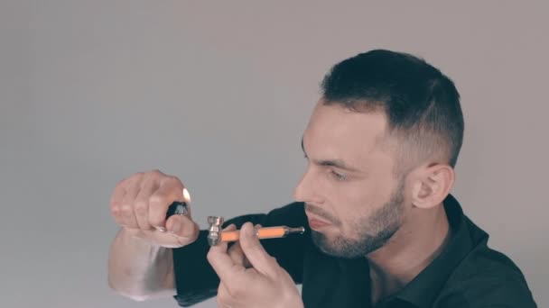 Junger Mann raucht Unkraut mit Pfeife im Haus — Stockvideo