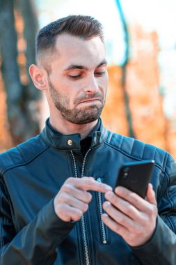 Autumn Park 'ta akıllı telefon kullanan yakışıklı adam.