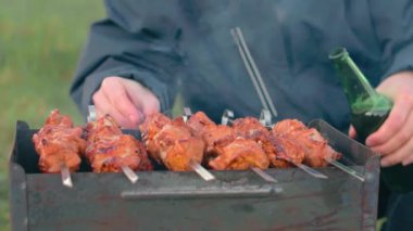 Barbekü yapan adam dışarıda et yiyor.