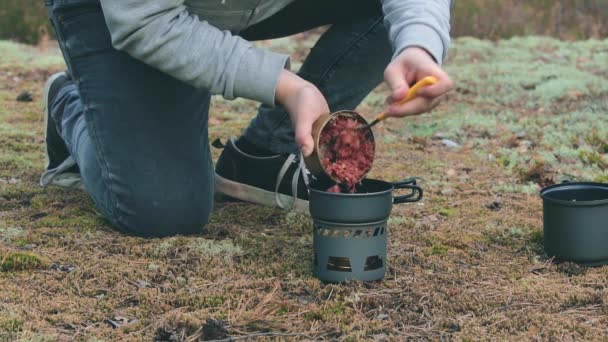 Vandrare kokar pasta med konserverad gryta i en skog — Stockvideo