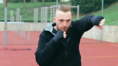 Genç Sakallı Adam dışarıda boks antrenmanı yapıyor.