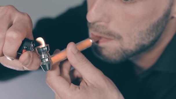 Молодий чоловік курить траву, користуючись трубкою в приміщенні — стокове відео