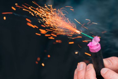 Kıvılcımlar ve dumanla elinde yanan maytap.