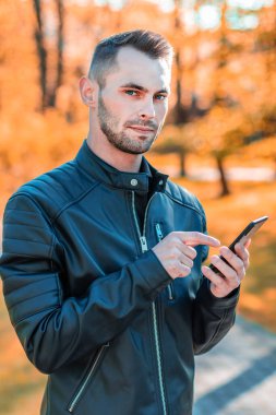 Autumn Park 'ta akıllı telefon kullanan yakışıklı adam.
