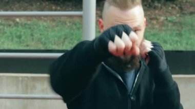 Genç Sakallı Adam dışarıda boks antrenmanı yapıyor.